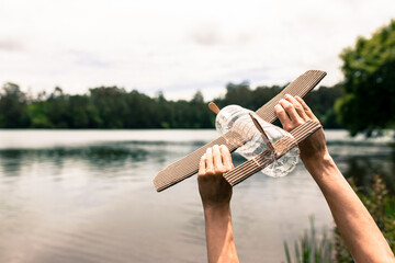 children's hands playing with a plane built with recycled material (wood, PVC bottles, cardboard)