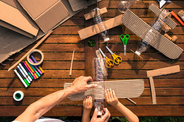 grandfather and grandson building airplanes with recycled material (cardboard, PVC bottles, wood). work ideas circular economy, recycling, environment
