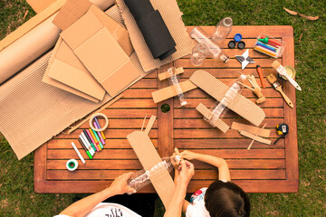 grandfather and grandson building airplanes with recycled material (cardboard, PVC bottles, wood). work ideas circular economy, recycling, environment
