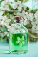 Obraz na płótnie Canvas Aromatic essential oil in glass bottle and flowers on blue background. Aromatherapy and spa concept. Refreshing fragrances for relaxation.