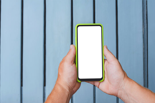 Close-up, Mockup of a smartphone in the hands of a man against the background of a gray rhythmic wooden wall.