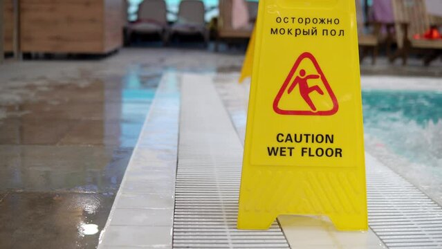 The inscription in Russian carefully wet floor. Yellow sign warning that the floor is slippery near the pool