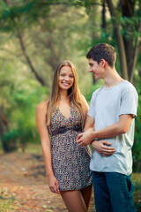 Fototapeta premium Guy looks at his beloved laughing girl. Caring young man holding the hand of a minor beloved in the park