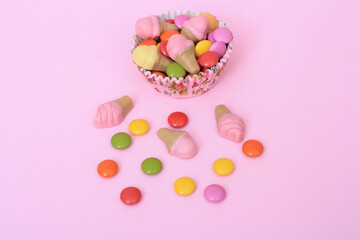 Fototapeta na wymiar Bright multi colour chocolate gemes on pink background