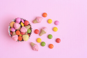 Fototapeta na wymiar Bright multi colour chocolate gemes on pink background