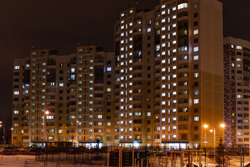 Fototapeta na wymiar Multi-storey houses night. Windows in apartments glow at night in winter