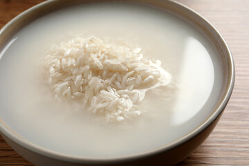 Rice soaked in water on wooden table, closeup