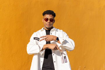 black latin man with red sunglasses dancing in front of the camera with a yellow background