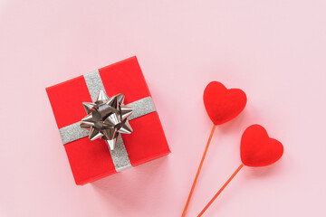 Gift in a red box and two toy hearts on pink background. Valentines day concept. Top view, flat lay