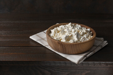 Cottage curd cheese in a bowl on old wooden table.