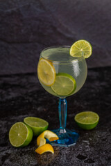 Alcoholic drink gin and tonic cocktail with lemon and ice on concrete background. space for text