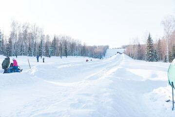 Sledding downhill in winter. Winter entertainment. Healthy lifestyle. People are rolling down the hill. Holidays. Family trip.