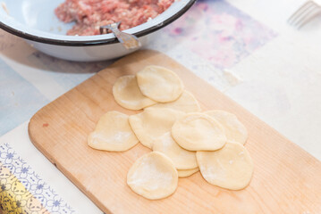 Sculpt dumplings. Traditional Russian cuisine. National dish. Hand molding. Dough with meat. Woman sculpt dumplings with her hands.