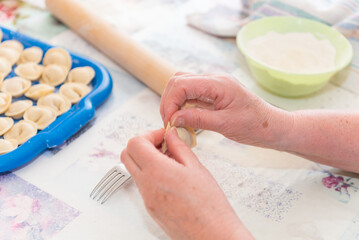 Sculpt dumplings with your hands. The woman is preparing food. Traditional Russian cuisine. Raw dumplings. Delicious homemade food.