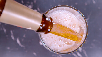 TOP DOWN: IPA beer gets poured out of a brown vintage bottle and into a glass. - obrazy, fototapety, plakaty
