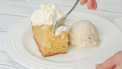 Slice of fresh baked apple cake with biscuit base and sliced apples and whipped cream topping...