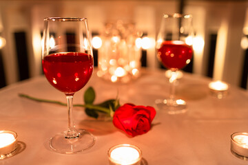 romantic candle light dinner setting with wine and roses