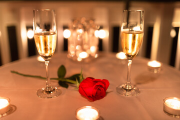 Two glasses of champagne with candles and red rose. Valentine's Day, romantic date night concept. 