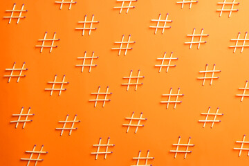 Hashtag symbols made of wooden matches on orange background, flat lay