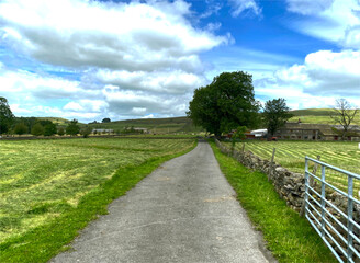 Fototapeta na wymiar Tarmac road, leading to fields and farms, on a cloudy day near the Skipton Old Road, Colne, UK