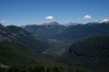 View of the mountains, valley and green forest, under a clear blue sky. 
