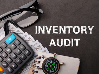 Top view calculator,glasses,compass and banknotes with text INVENTORY AUDIT on black background.