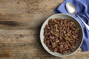 Fried minced meat, spoon and napkin on wooden table, top view. Space for text