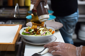 Kitchen employee preparing salad for customer food order
