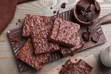 Delicious chocolate brownies on wooden table, flat lay