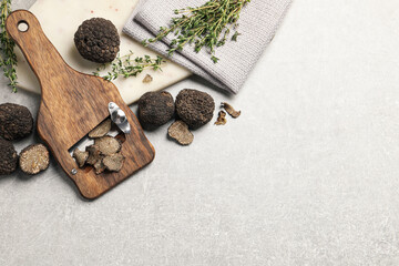 Fresh black truffles, slicer and thyme on grey table, flat lay. Space for text
