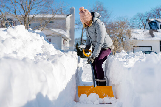 Woman shoveling snow out of driveway. 
