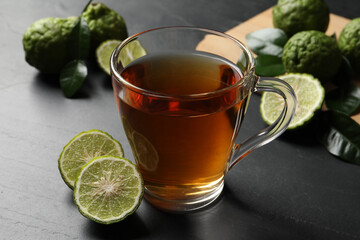 Glass cup of tasty bergamot tea and fresh fruits on black table