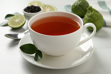 Cup of tasty bergamot tea on white table, closeup