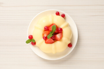 Delicious semolina pudding with berries on white wooden table, top view