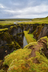 Green and beautiful Fjaðrárgljúfur canyon reaching the coastal plains near Kirkjubæjarklaustur village, South Coast of Iceland	