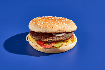 Beef burger blue background with hard shadow. American junk food minimal style. Hamburger trendy style.  Simple burger colour background.