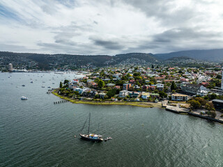 High angle aerial drone view of Battery Point, a waterfront residential suburb near the CBD of Hobart, capital city of the island and state of Tasmania, Australia. Sailboat in the foreground. - obrazy, fototapety, plakaty