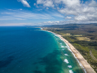 Stunning high angle aerial panoramic drone view of Lagoons Beach Conservation Area and the A3 Tasman Highway near the village of Scamander on the east coast of Tasmania, Australia on a sunny day.