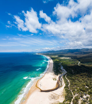 Stunning high angle aerial panoramic drone view of Lagoons Beach Conservation Area and the A3 Tasman Highway near the village of Scamander on the east coast of Tasmania, Australia on a sunny day.