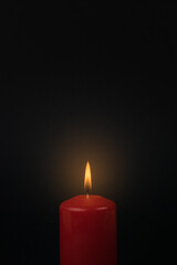 A bright burning candle on a black background.