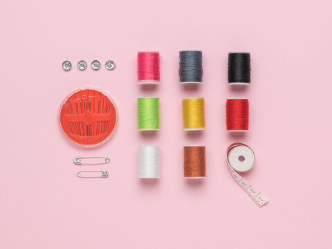 A set for home sewing and embroidery on a pink background. Flat lay.