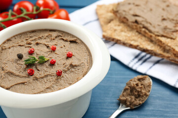 Tasty liver pate with pepper and herb on blue table, closeup. Space for text