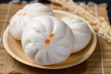 Steamed Chinese bun stuffed with minced pork, egg yolk or sweet on natural plate, Asian food
