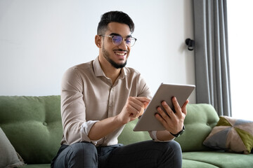 Young man using digital tablet computer sitting on sofa at home office