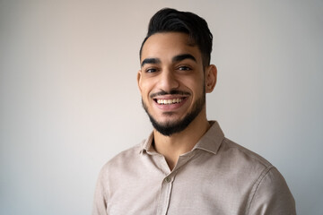 Headshot portrait of young adult smiling Indian man over blank copy space
