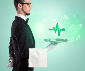 Handsome young waiter in tuxedo holding healthcare icons on tray