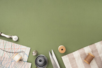 Pattern, fabric and sewing accessories on a green paper background, flat, lay, top view, copy space. A tailor or seamstress desk. Sewing concept, background. Tailoring of designer clothes