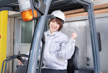 フォークリフトに乗る女性作業員　ガッツポーズ  © oka