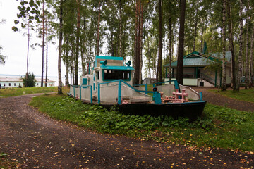 Fototapeta na wymiar wooden old boat on land as decor, recreation center in the forest in summer