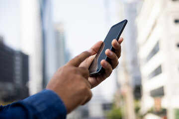 Businessman hand holding using smartphone on urban city background.